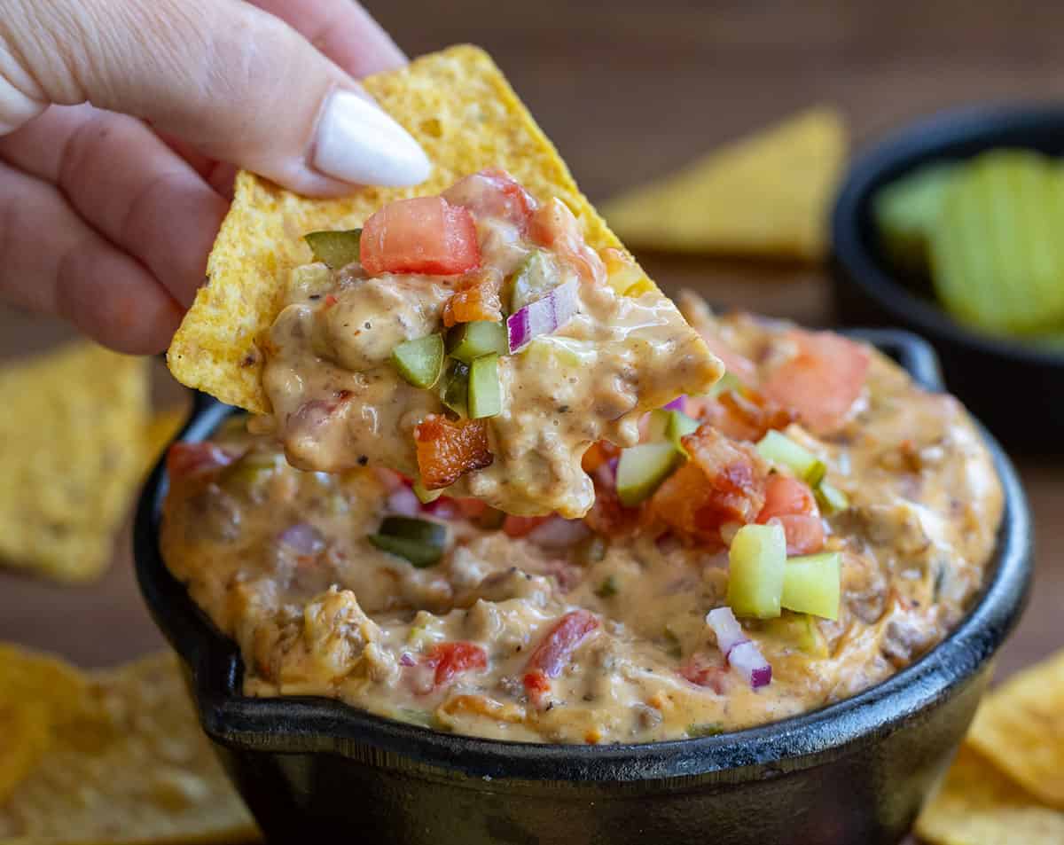 Hand picking up a chip loaded with Cheeseburger Dip.