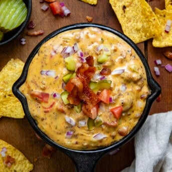 Mini skillet of Cheeseburger Dip on a wooden table surrounded by chips.