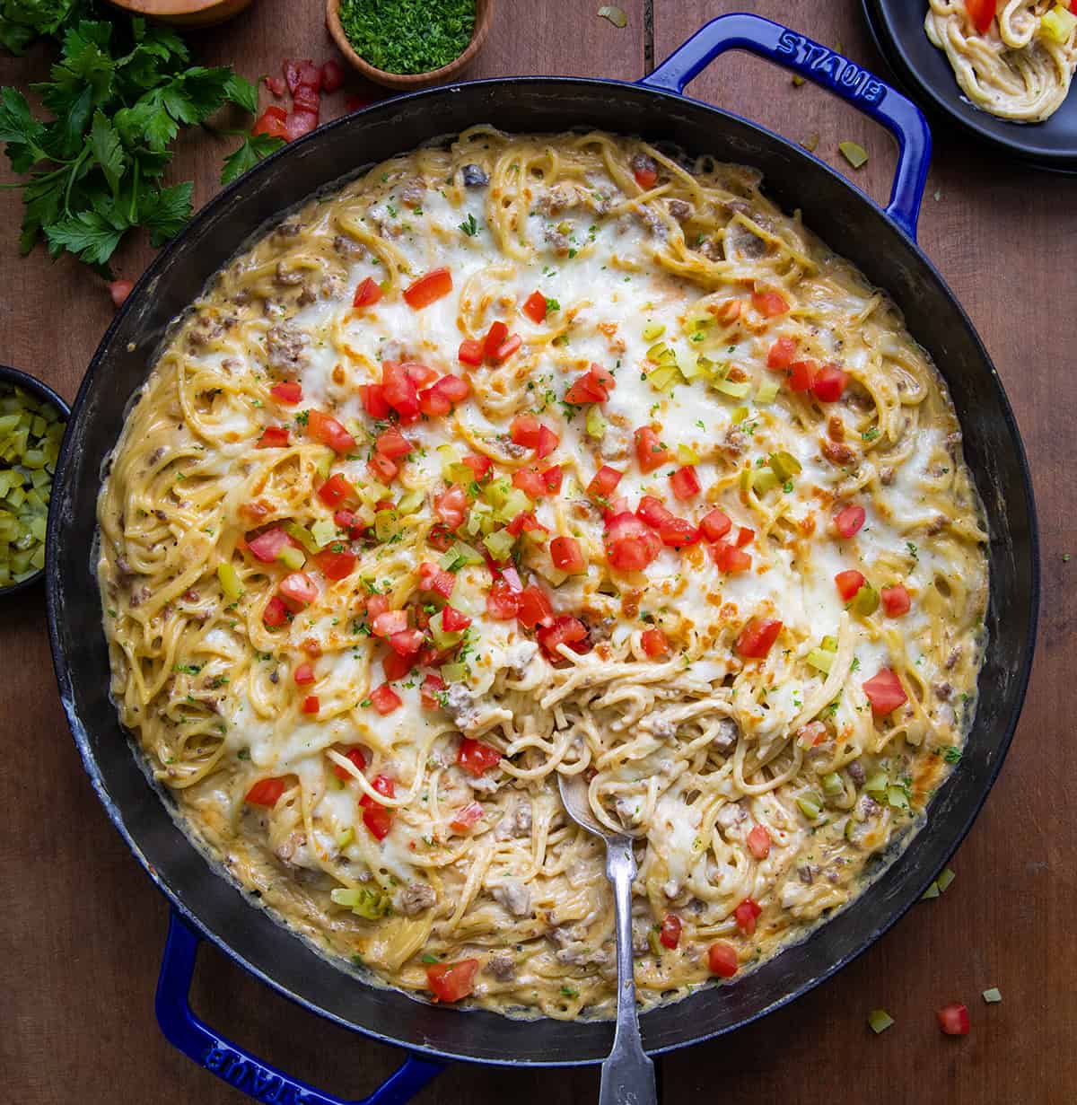 Skillet of Cheeseburger Tetrazzini on a wooden table with a spoon in it from overhead.