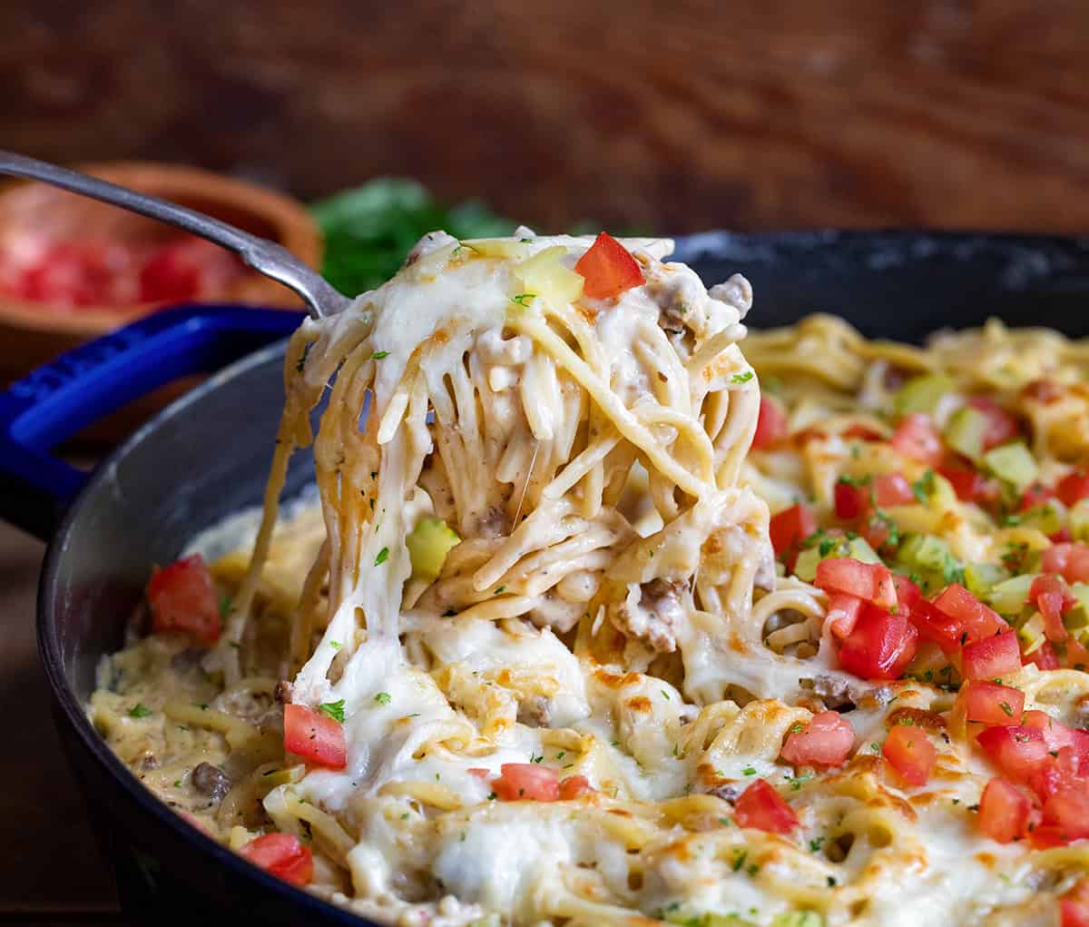 Scooping up a portion of Cheeseburger Tetrazzini from the skillet close up.