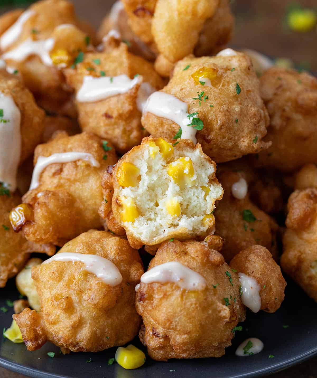 Corn nuggets stacked on a plate with one halved showing the inside texture.