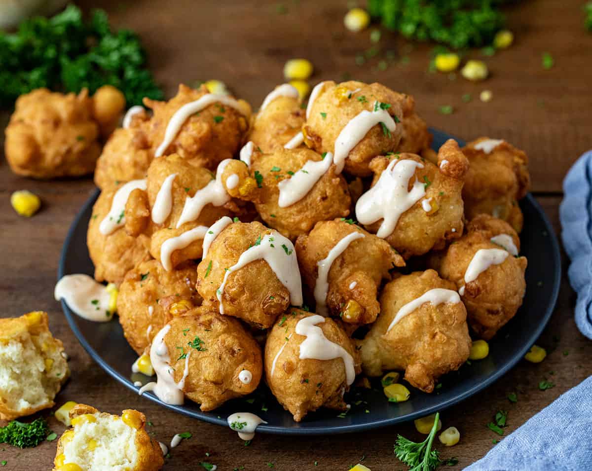 Plate of Corn Nuggets with sauce drizzled over top.