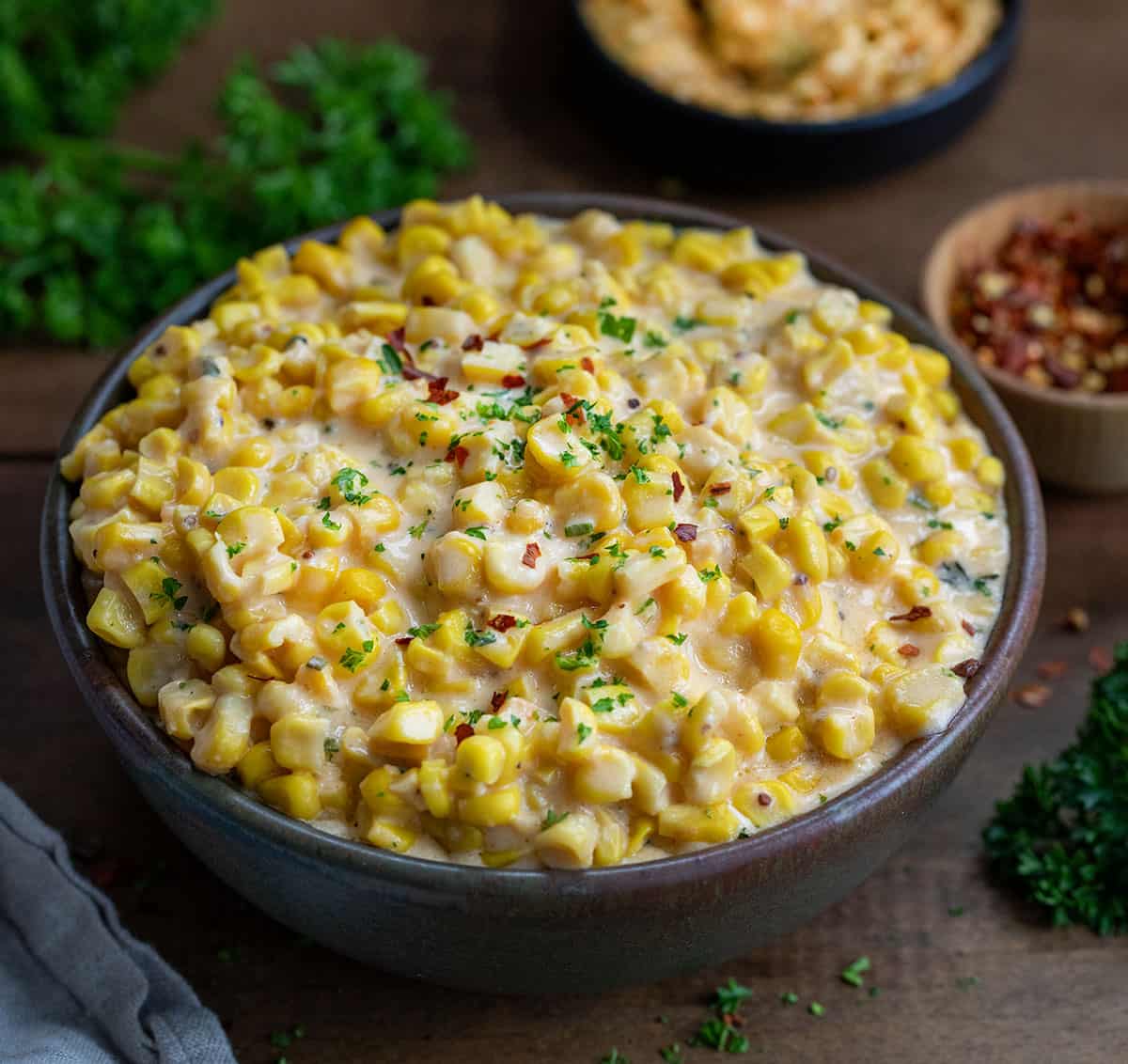 Bowl of Cowboy Butter Creamed Corn on a wooden table.