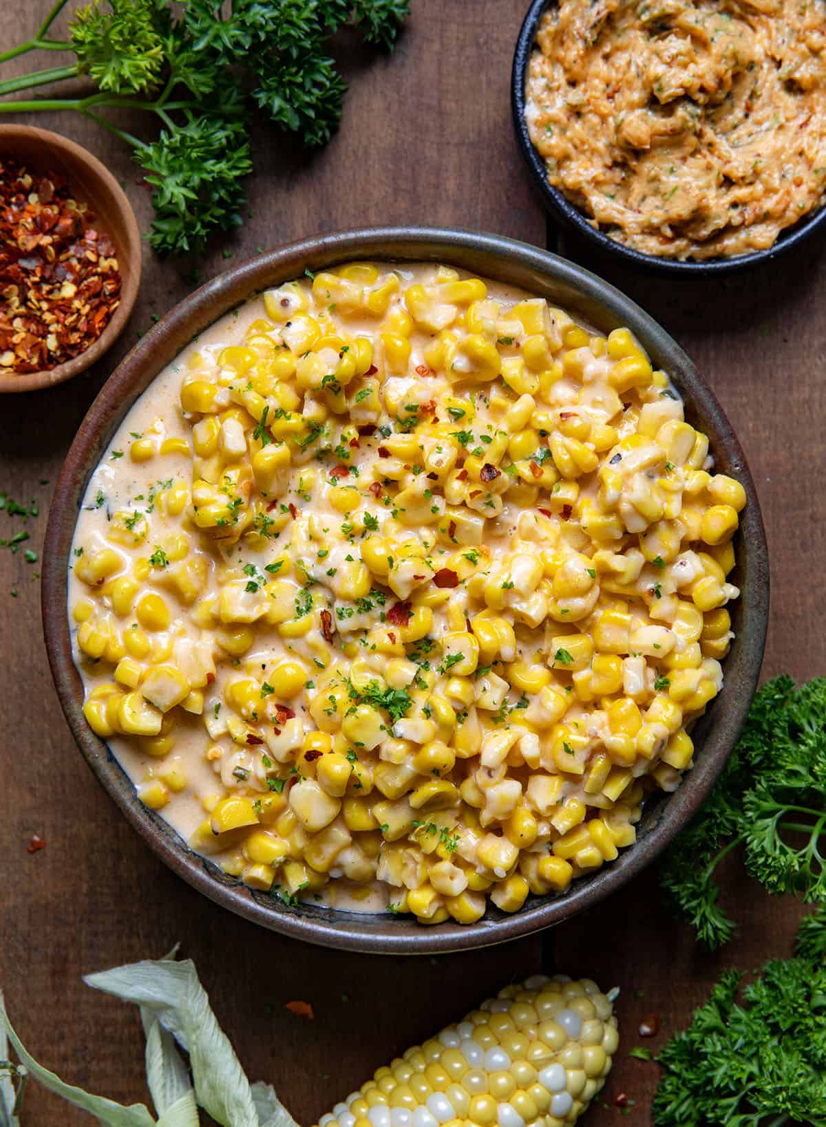 Bowl of Cowboy Butter Creamed Corn on a wooden table from overhead.