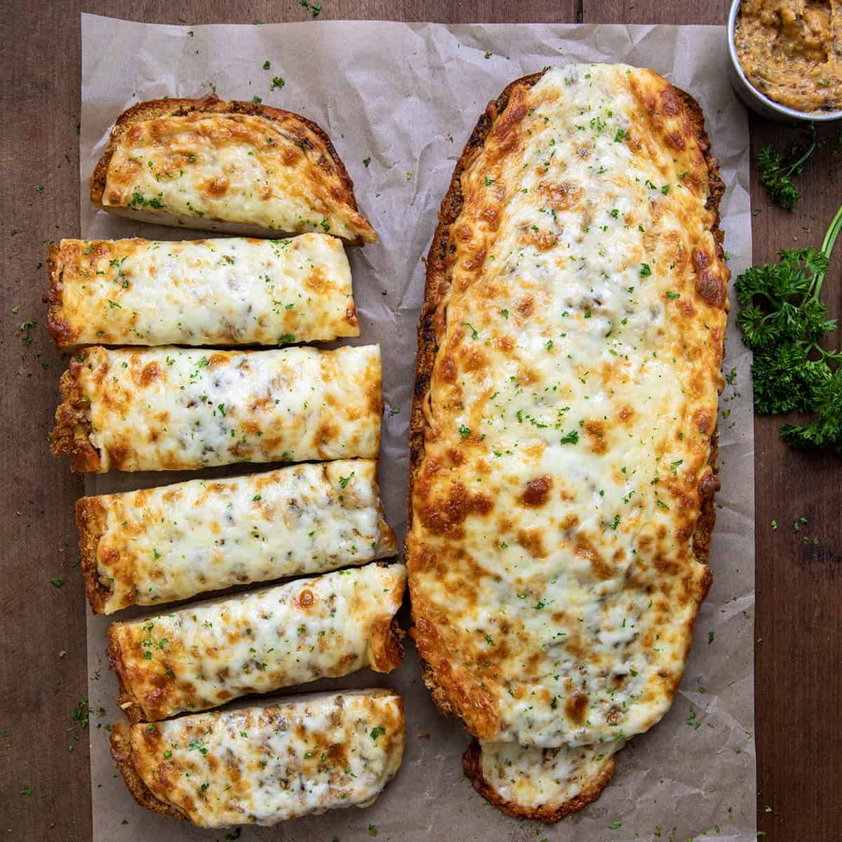 Cowboy Butter Garlic Bread with one half whole and the other cut into slices on a wooden table from overhead.