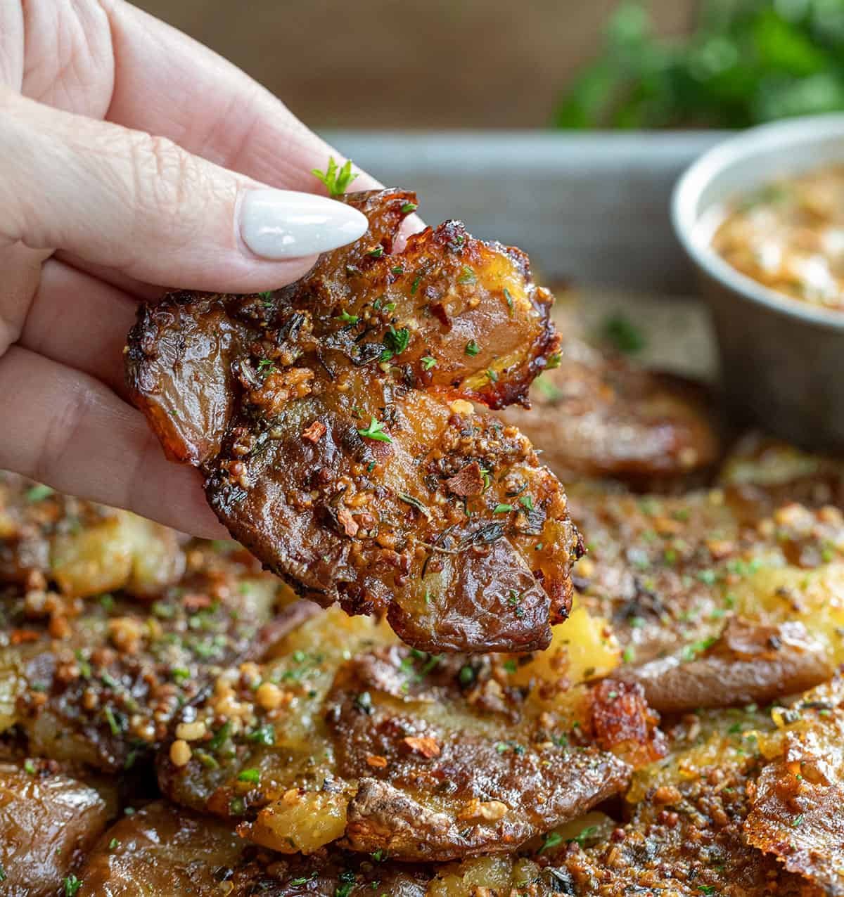 Hand holding one Cowboy Butter Smashed Potatoe.