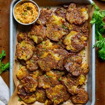 Pan of Cowboy Butter Smashed Potatoes on a wooden table from overhead.