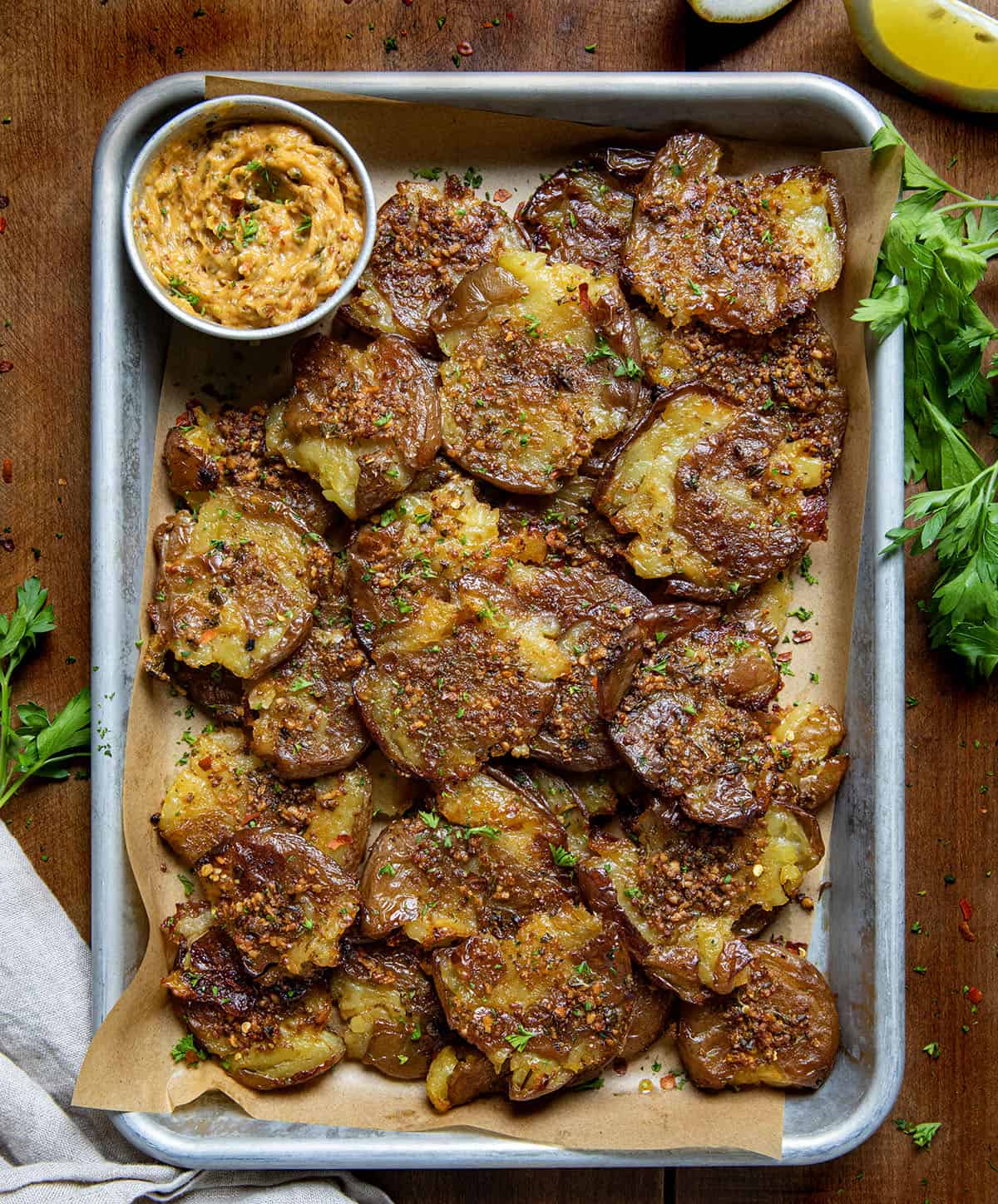 Pan of Cowboy Butter Smashed Potatoes on a wooden table from overhead.