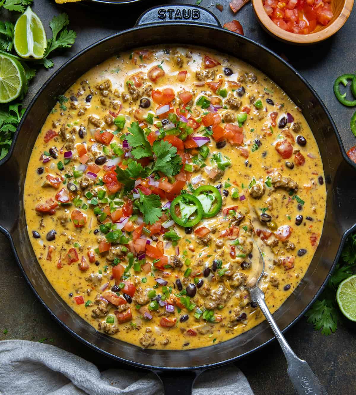 Skillet of spicy Cowboy Queso on a wooden table from overhead. 