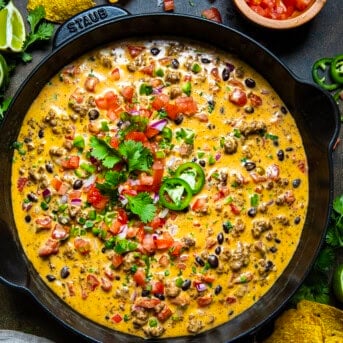 Skillet of spicy Cowboy Queso on a wooden table from overhead.