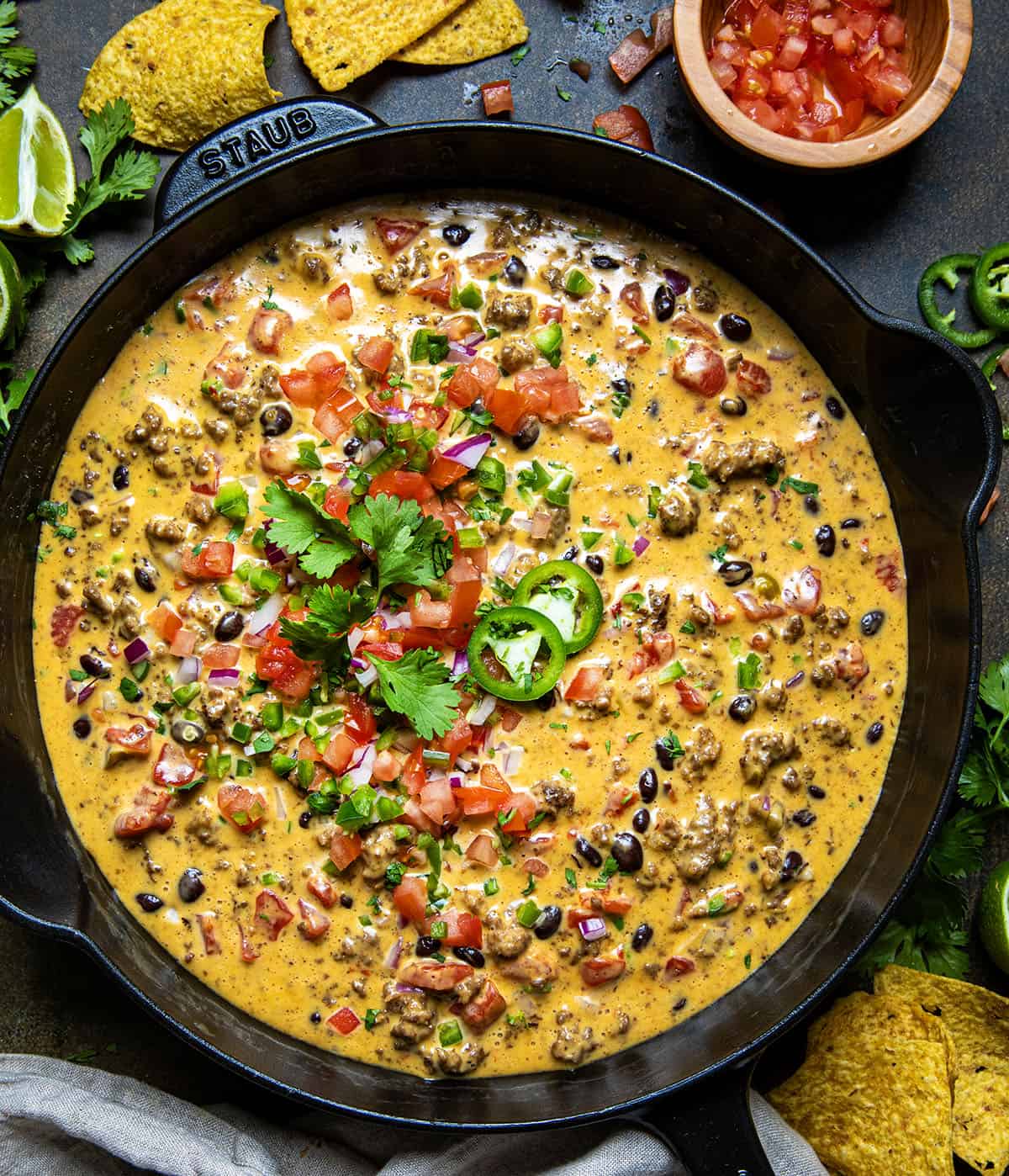 Skillet of spicy Cowboy Queso on a wooden table from overhead.