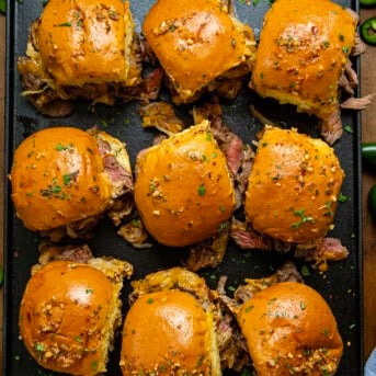 Looking down on a tray of Cowboy Steak Sliders on a wooden table.