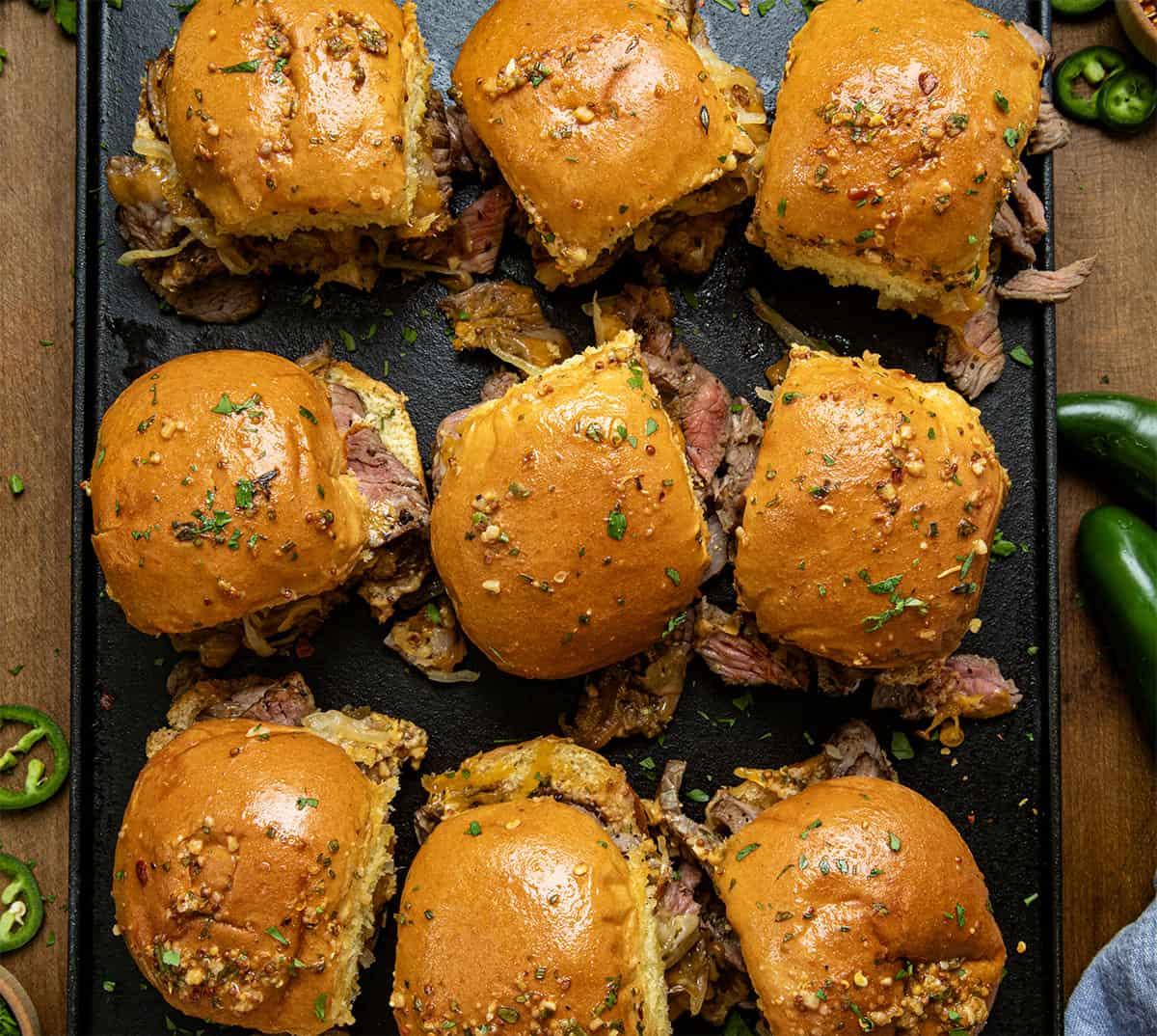 Looking down on a tray of Cowboy Steak Sliders on a wooden table.