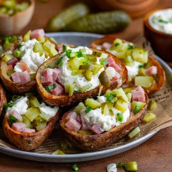 Platter of Ham and Pickle Potato Skins on a wooden table with pickles.
