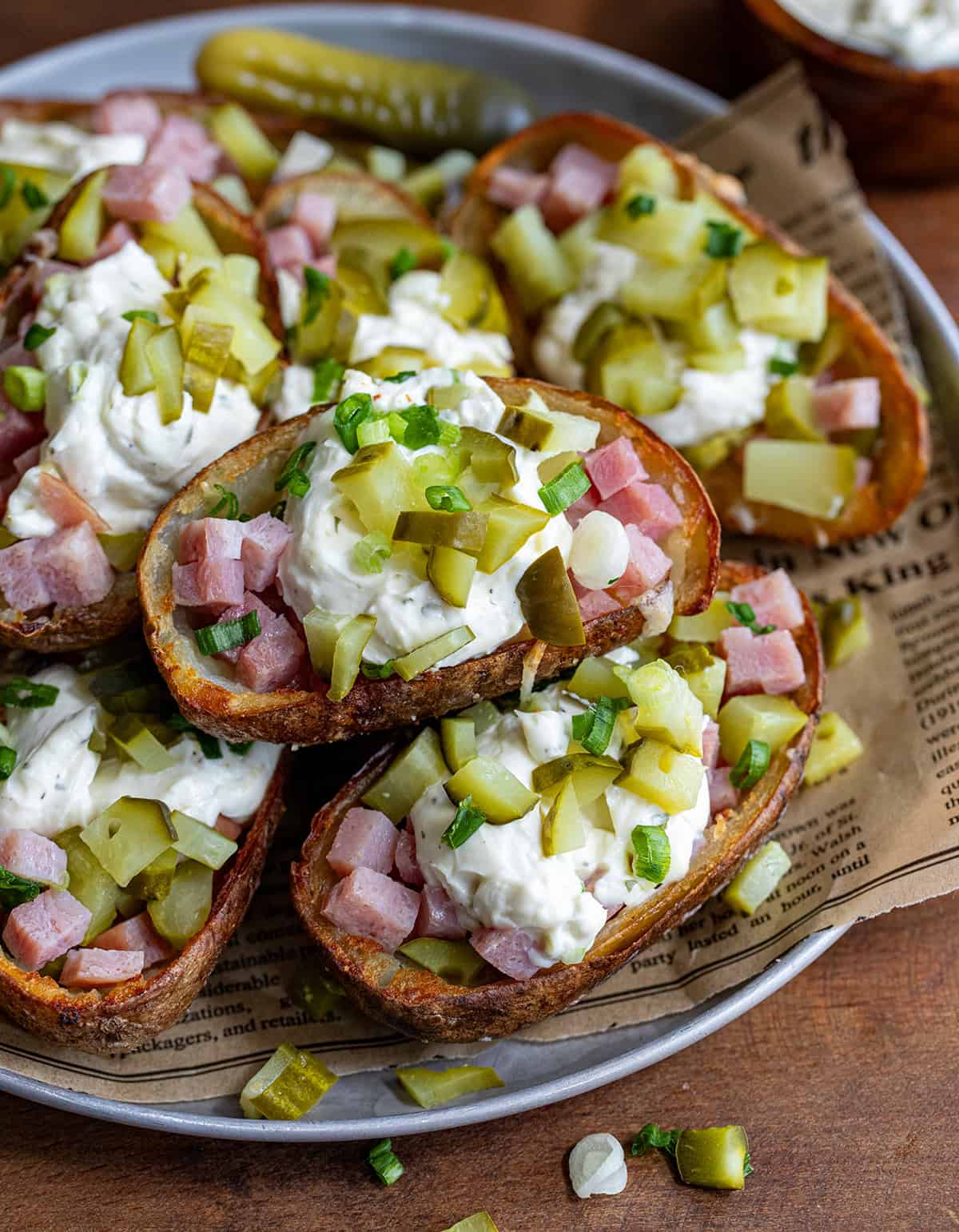 Platter of Ham and Pickle Potato Skins on a wooden table with pickles.