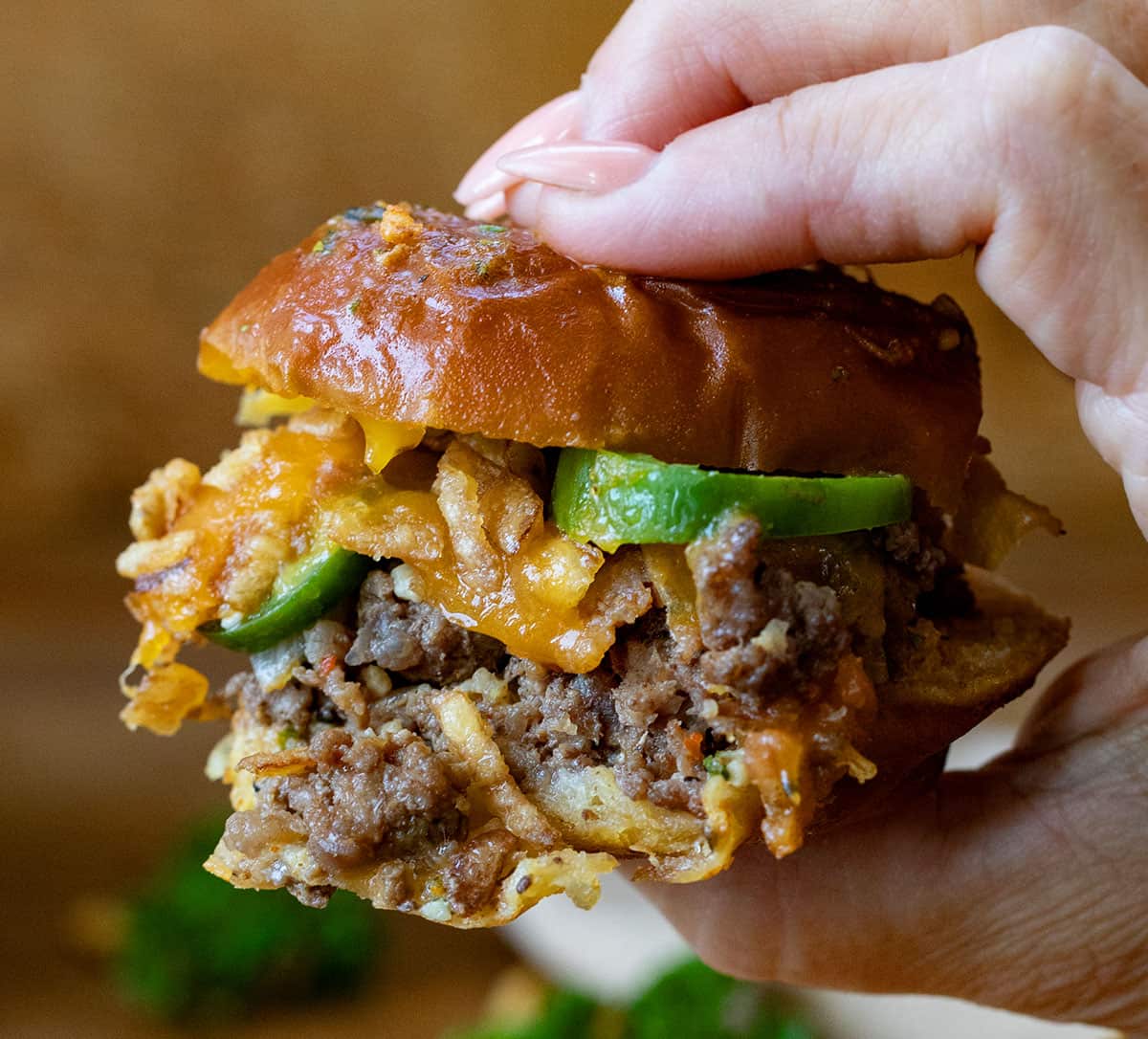 Hand holding a juicy Pretzel Cowboy Slider.