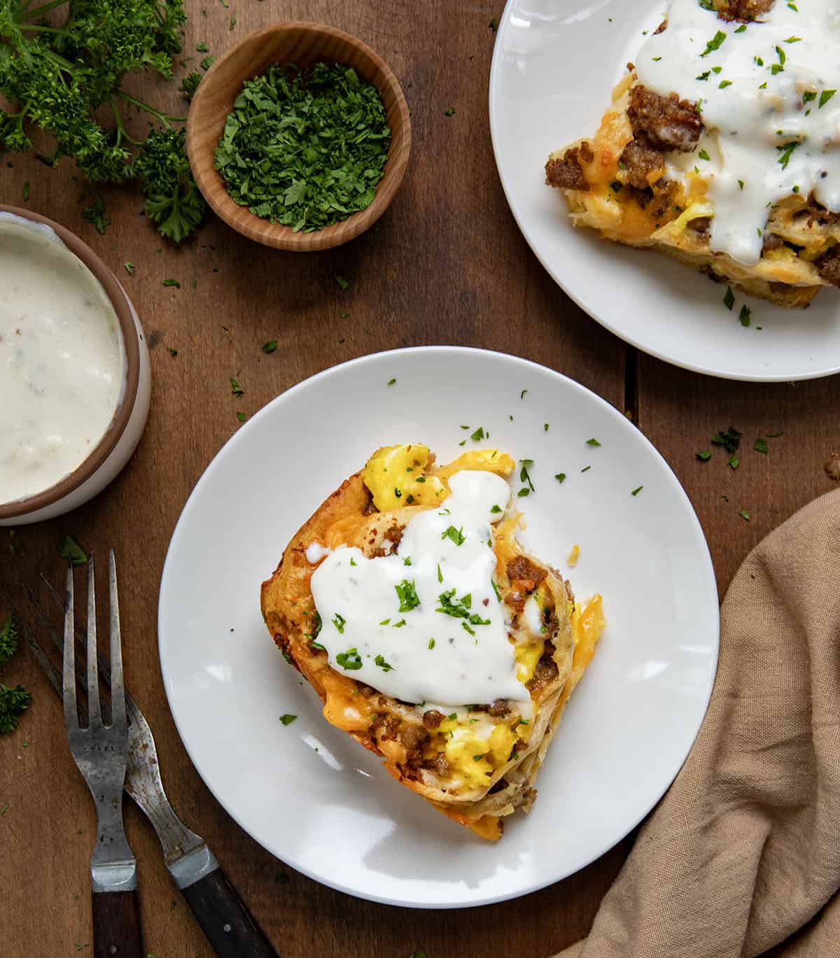 Plates of Breakfast Rolls on a wooden table set up for breakfast.