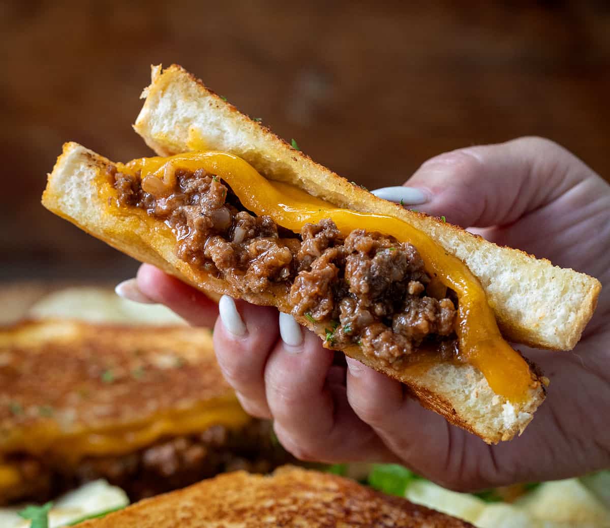 Hand holding half of a Sloppy Joe Grilled Cheese.