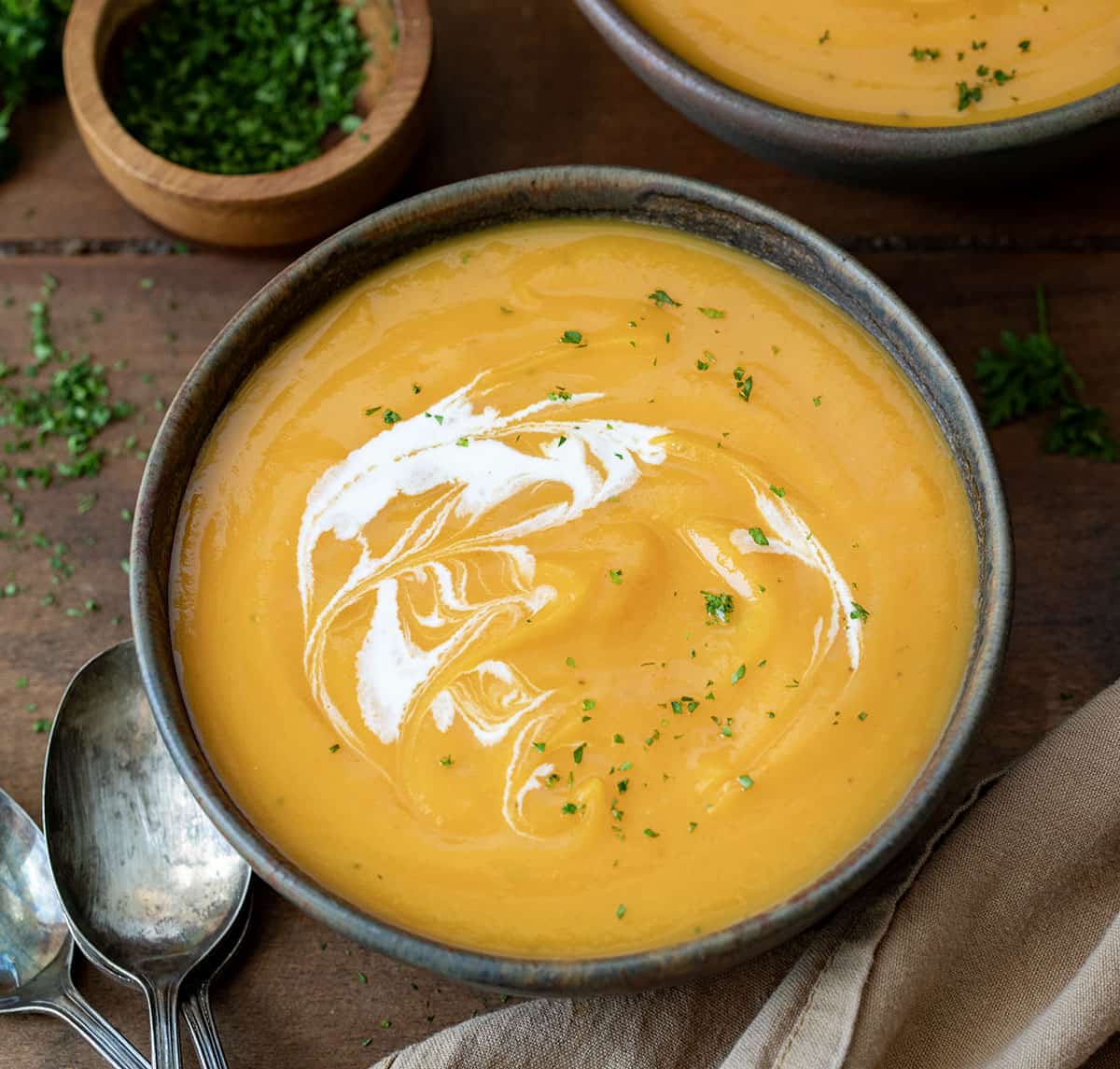 Bowls of Butternut Squash Soup on a wooden table.