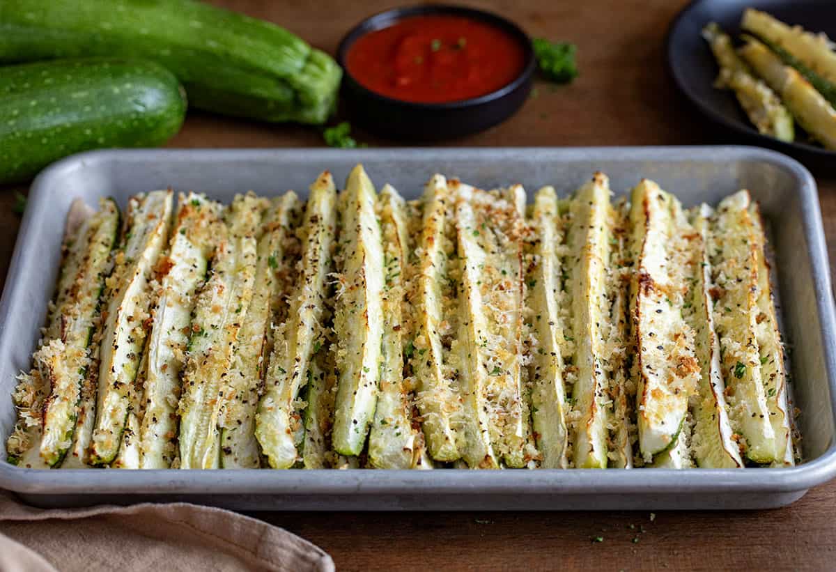 Tray of Baked Zucchini Sticks on a wooden table.