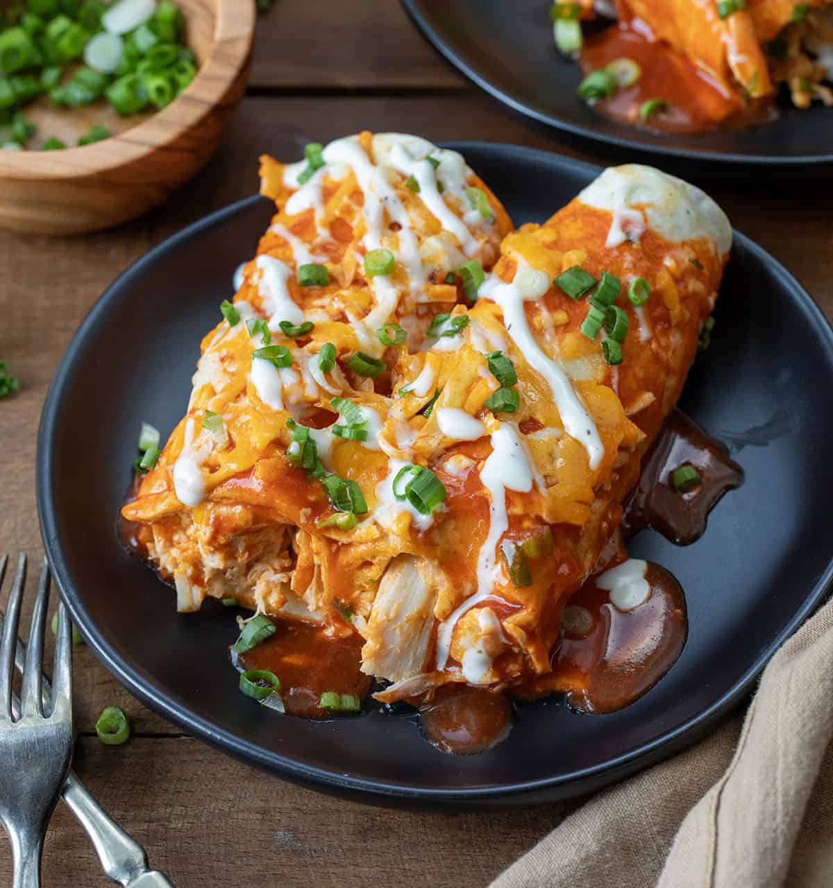 Cut into Buffalo Chicken Enchiladas on a black plate on a wooden table.