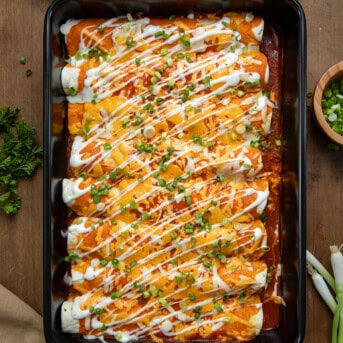 Buffalo Chicken Enchiladas in a black pan on a wooden table from overhead.