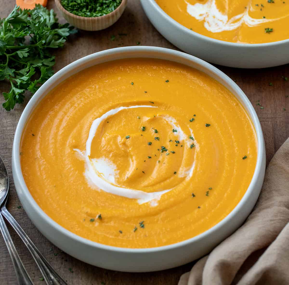 Bowls of Carrot Soup on a wooden table.