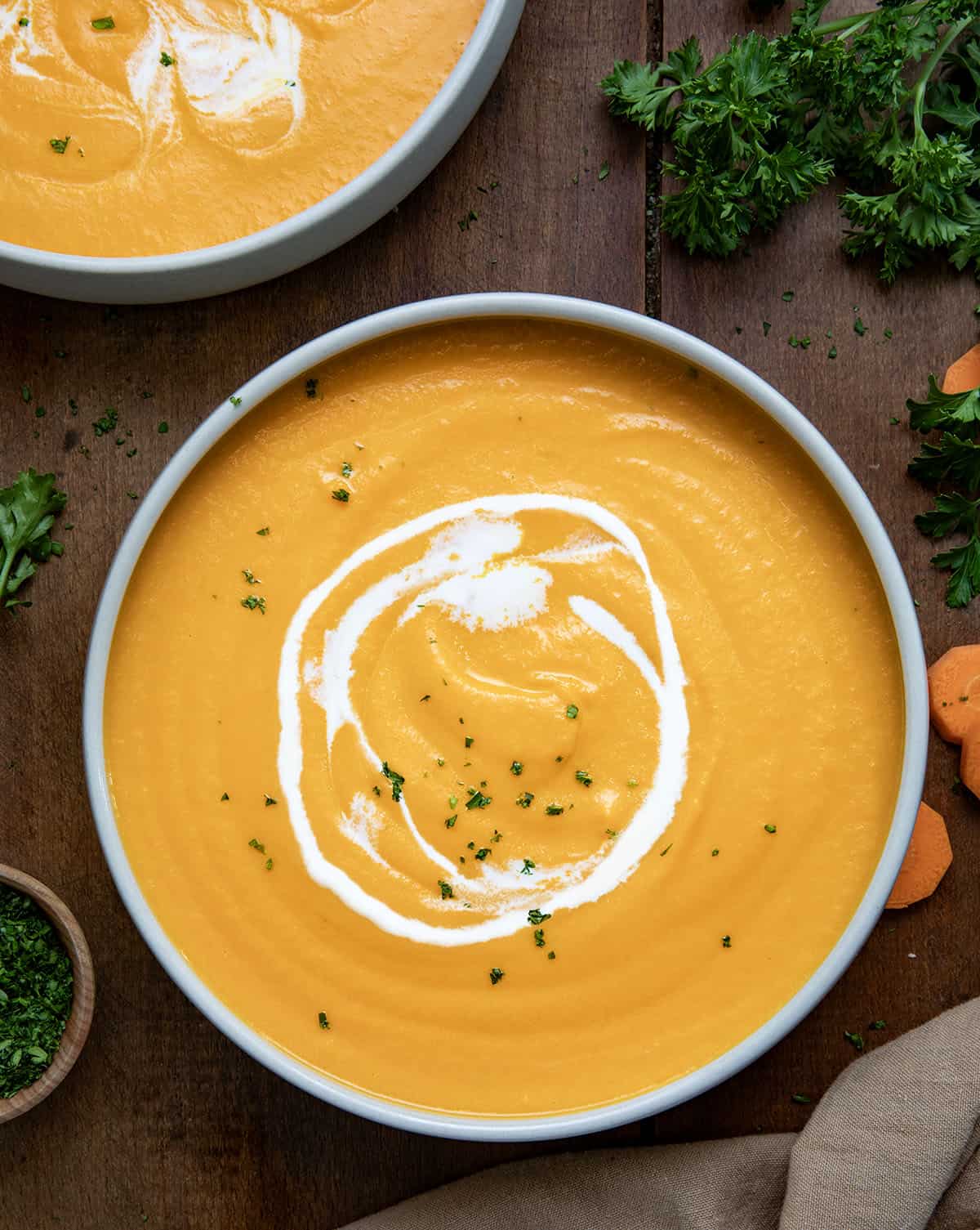 Bowls of Carrot Soup on a wooden table from overhead.