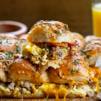 Cowboy Breakfast Sliders stacked on top of each other showing layers of sausage, bacon, cheese, and eggs.