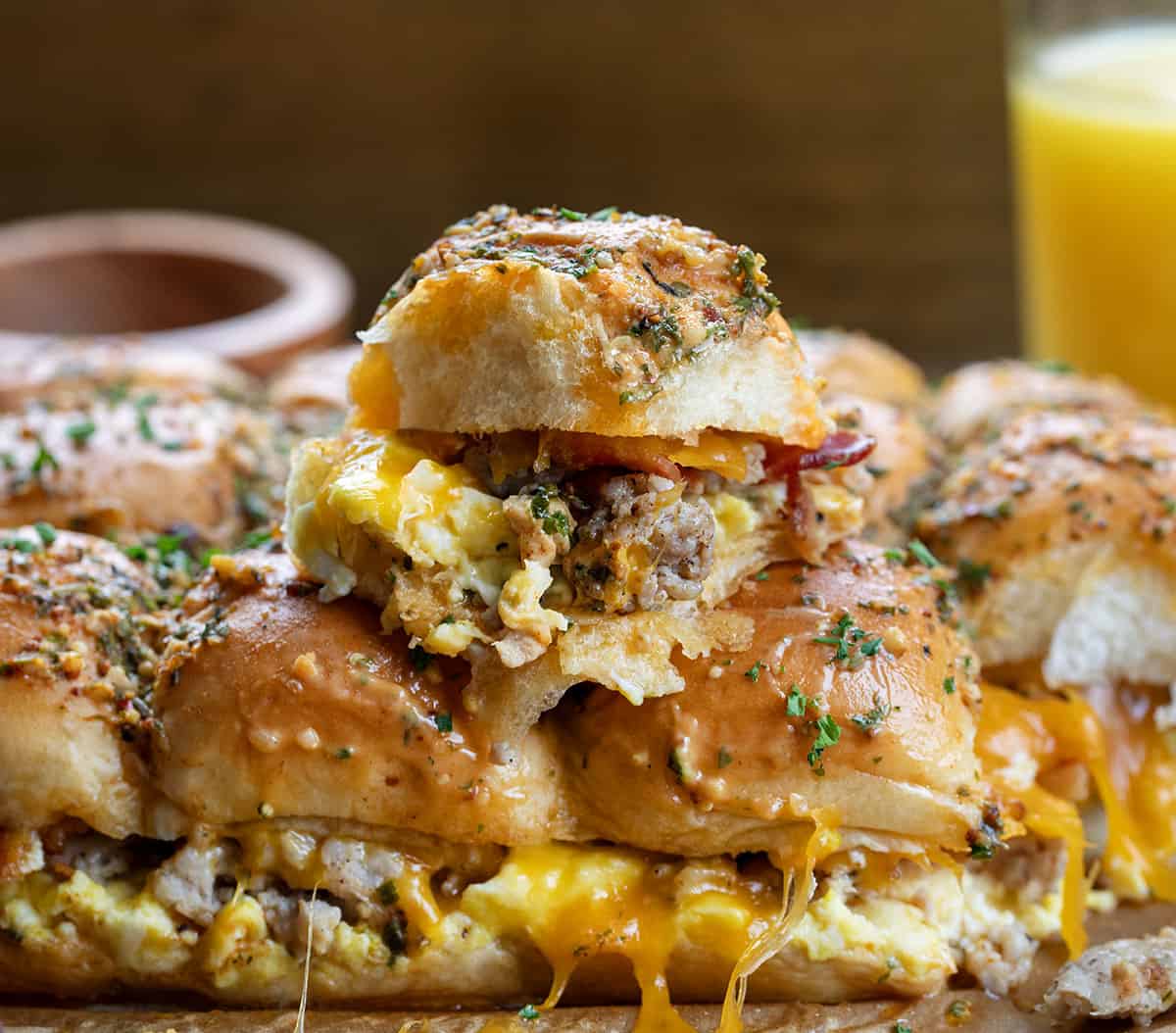 Cowboy Breakfast Sliders stacked on top of each other showing layers of sausage, bacon, cheese, and eggs.