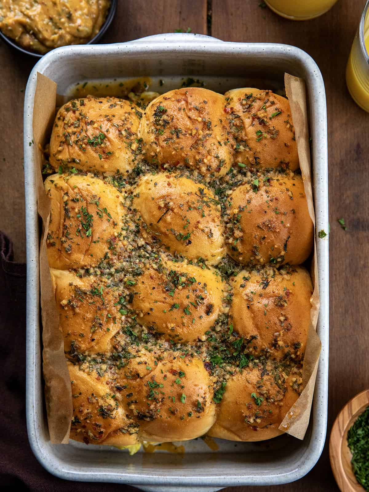 Sliders are one of the easiest ways to feed a crowd. They’re fun, customizable, and perfect for parties, game days, holidays, and family dinners! Looking down at Cowboy Breakfast Sliders on a wooden table with orange juice and cowboy butter.