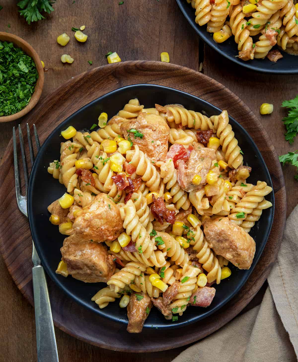 Black plates of Creamy Chicken and Bacon Pasta on a wooden table from overhead.