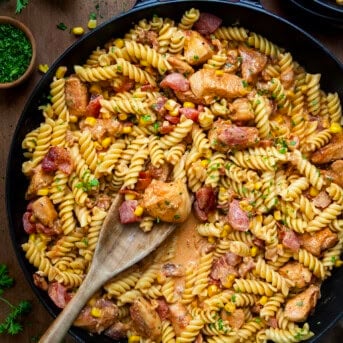 Skillet of Creamy Chicken and Bacon Pasta with a spoon in it from overhead.