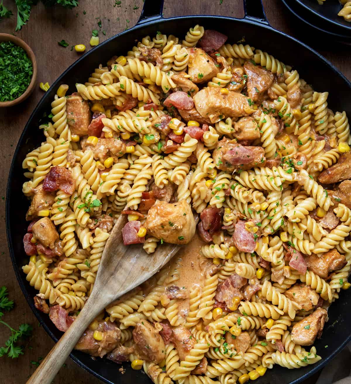 Skillet of Creamy Chicken and Bacon Pasta with a spoon in it from overhead.