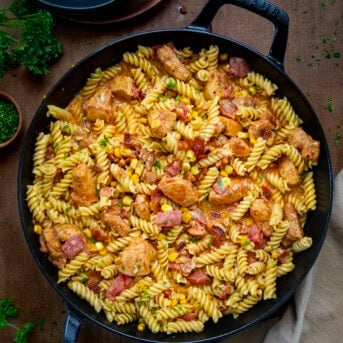 Skillet of Creamy Chicken and Bacon Pasta on a wooden table from overhead.