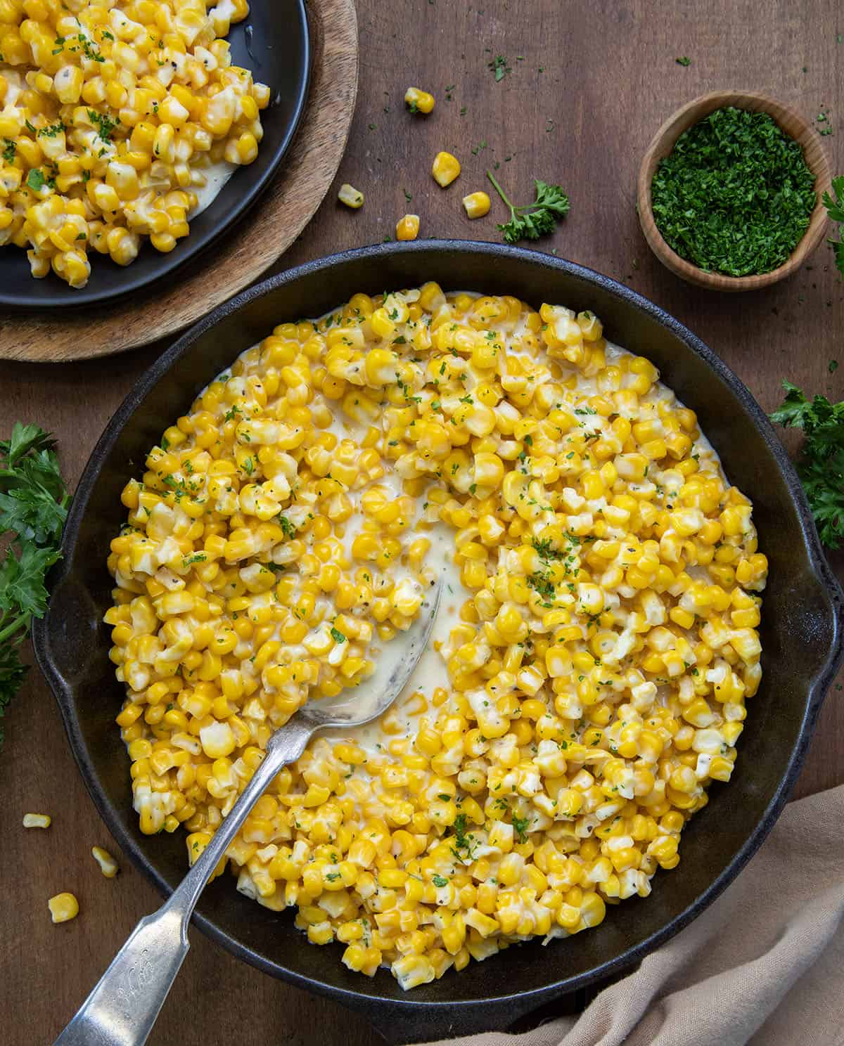 Honey Butter Skillet Corn on a wooden table with a spoon in it from overhead.