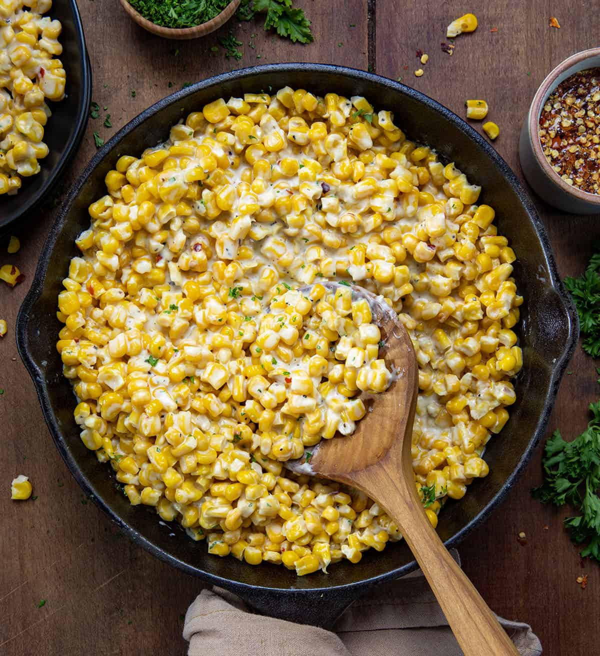 Hot Honey Butter Skillet Corn with a wooden spoon on a wooden table. 