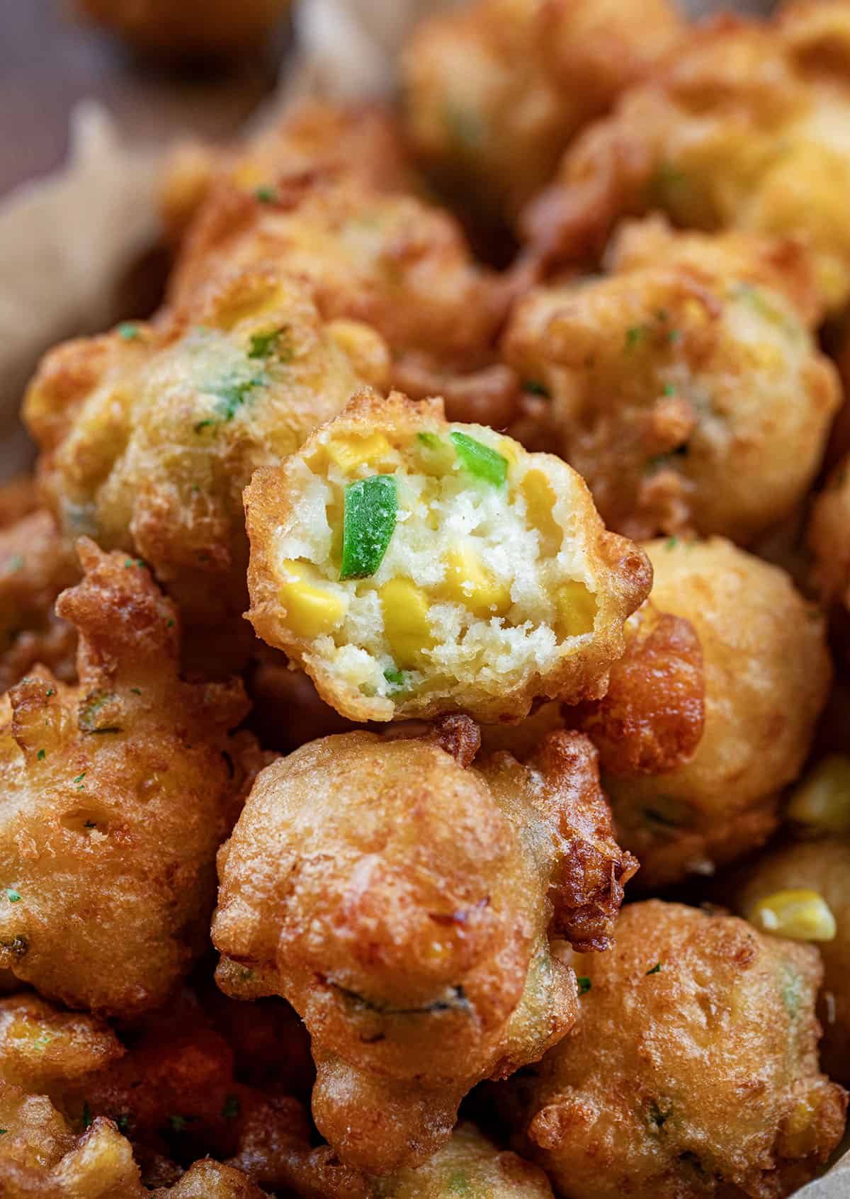 Pan of Jalapeno Corn Nuggets with one nugget halved showing tender dough inside.