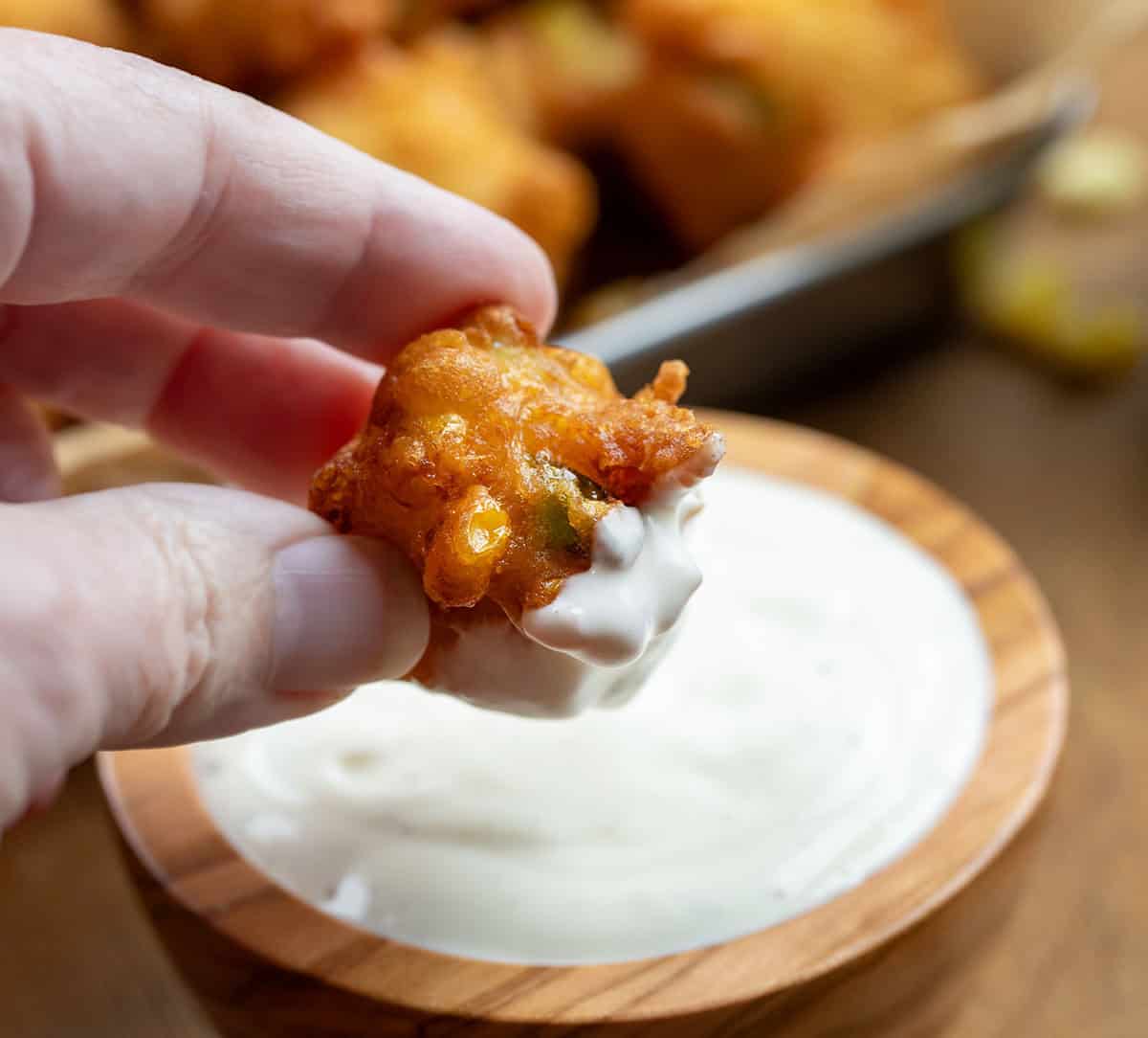 Dipping a Jalapeno Corn Nuggets into spicy ranch dressing.