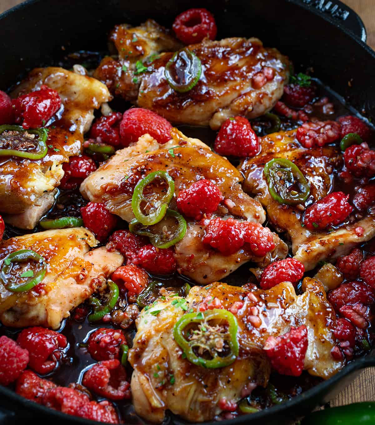 Skillet of Jalapeno Raspberry Chicken covered in fresh raspberries and jalapeno.