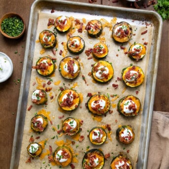 Sheet pan full of Loaded Zucchini Bites on a wooden table from overhead.