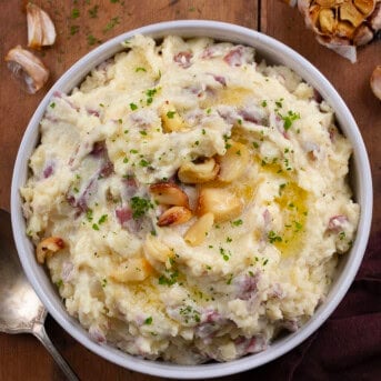 Bowl of Roasted Garlic Mashed Potatoes on a wooden table from overhead.