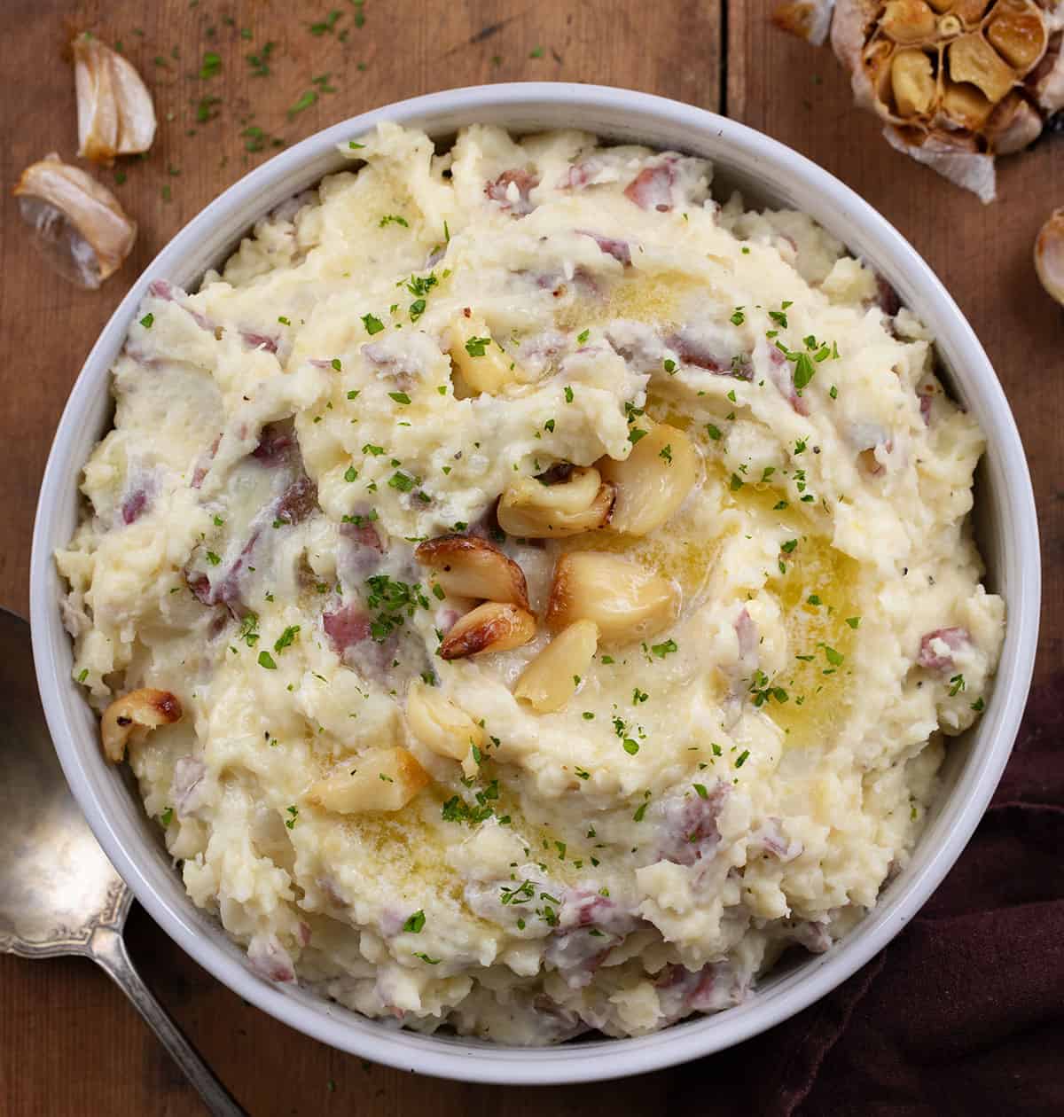 Bowl of Roasted Garlic Mashed Potatoes on a wooden table from overhead.