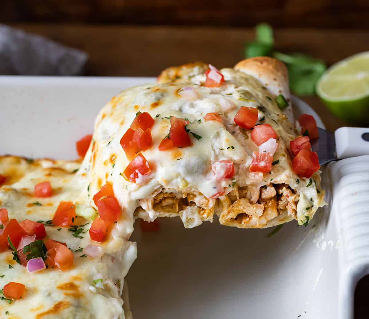 Scooping up a White Chicken Enchilada from casserole pan.