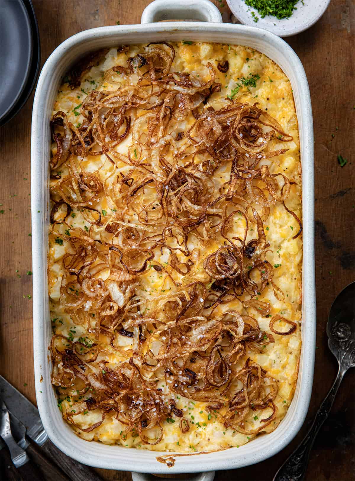 Pan of French Onion Funeral Potatoes on a wooden table from overhead.