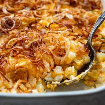 Spoon scooping out some French Onion Funeral Potatoes from pan.