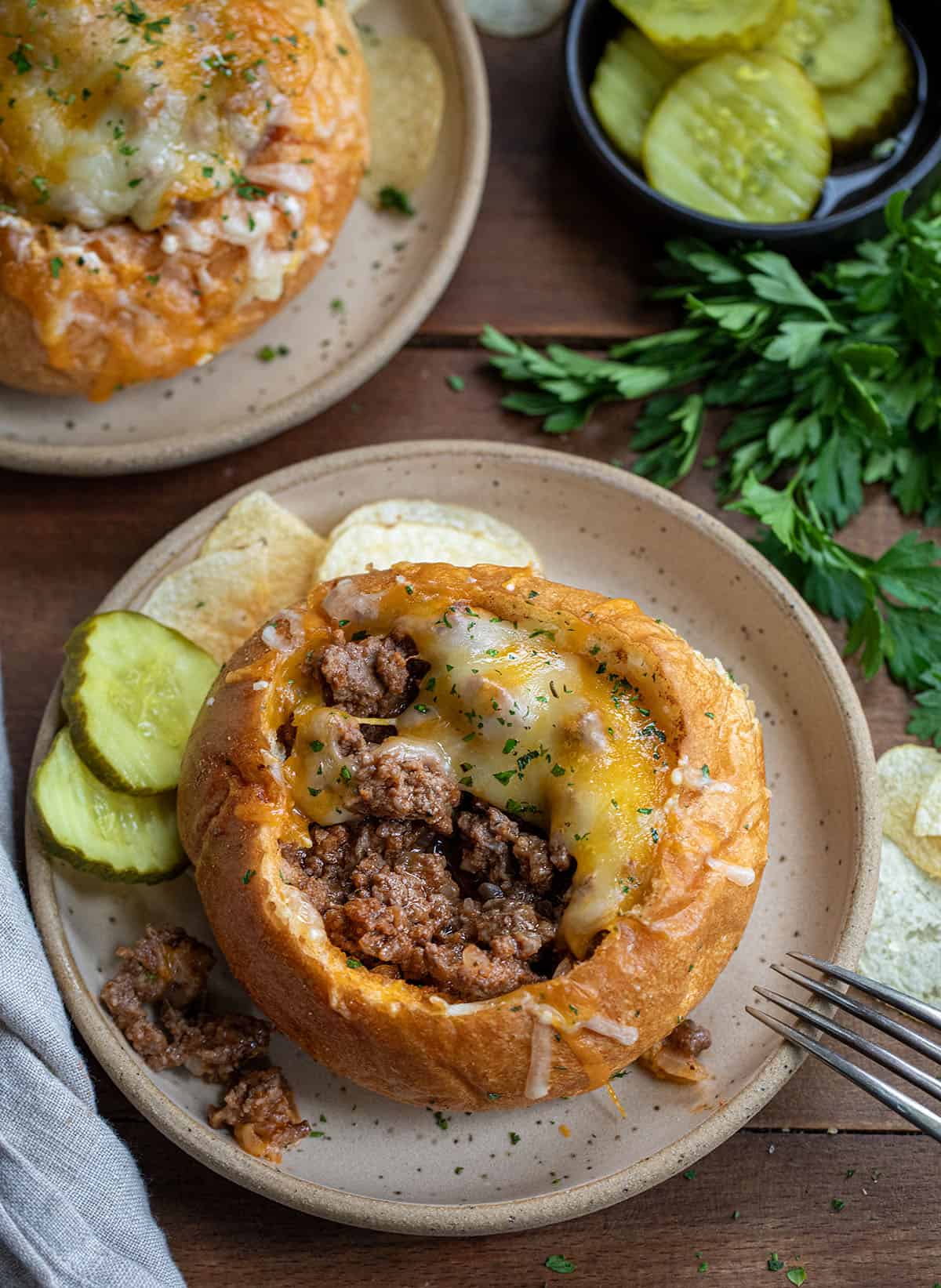 Partially eaten Sloppy Joe Bread Bowl on a plate on a wooden table.