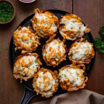 Skillet full of Buffalo Chicken Smashed Potato Cups on a wooden table from overhead.