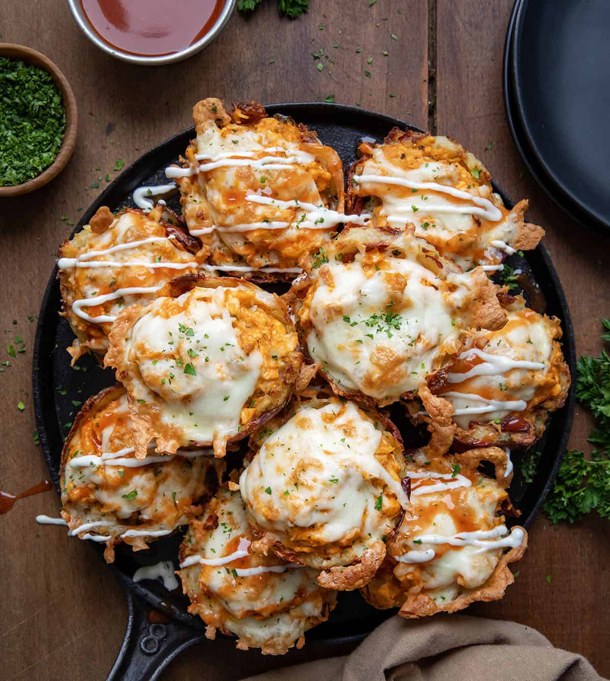 Skillet full of Buffalo Chicken Smashed Potato Cups on a wooden table from overhead.