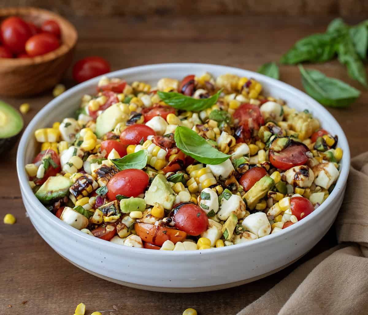 Bowl of Caprese Corn Salad on a wooden table.